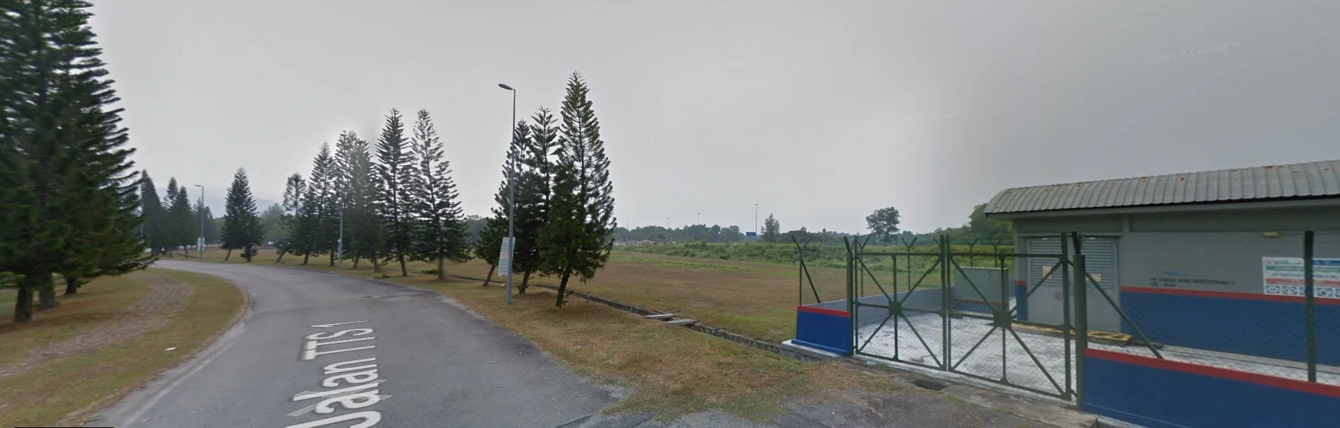 Jalan TTS 1/1 beside the site, with mature trees and the existing utility building